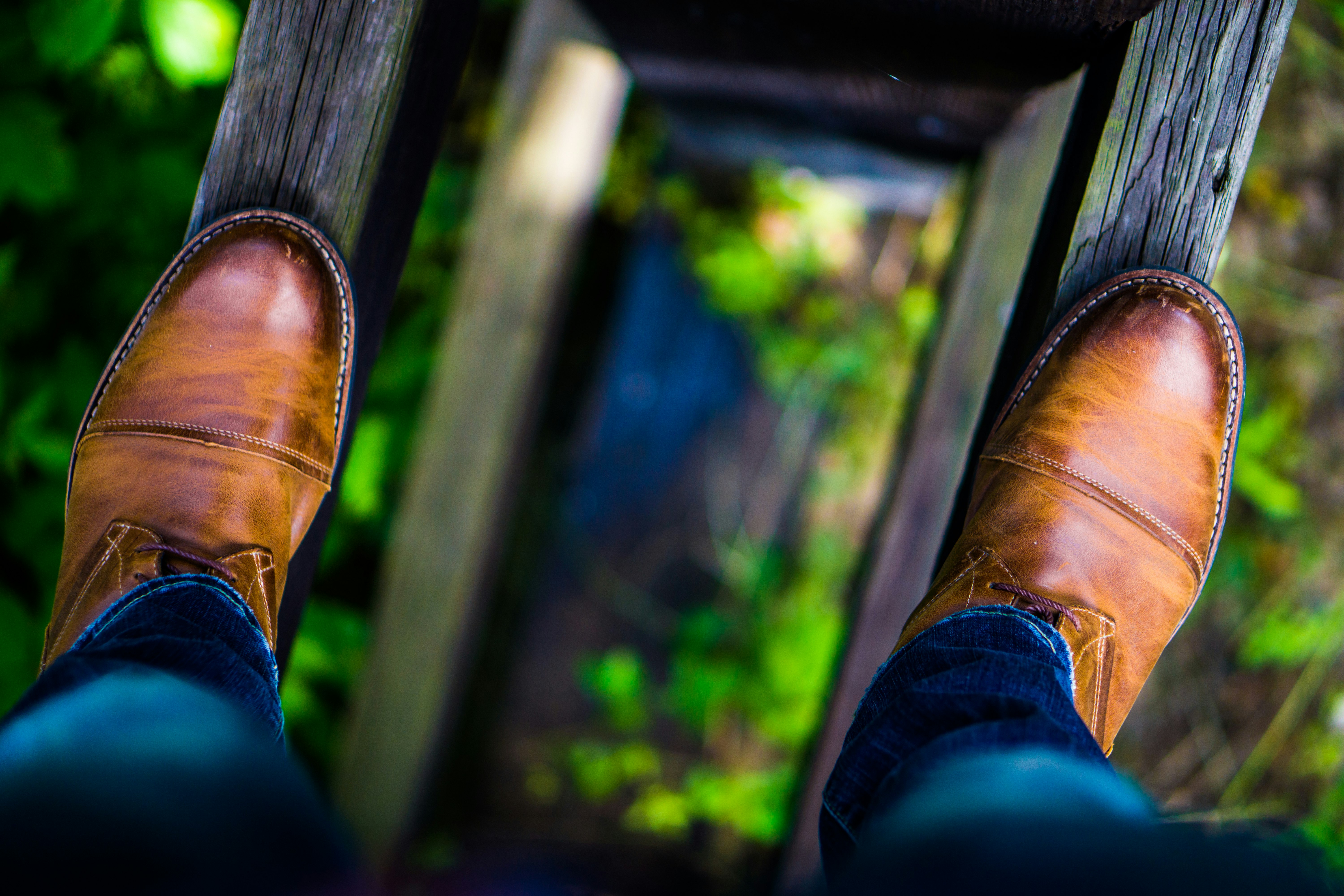 man wearing brown leather dress shoes stepping on brown wood